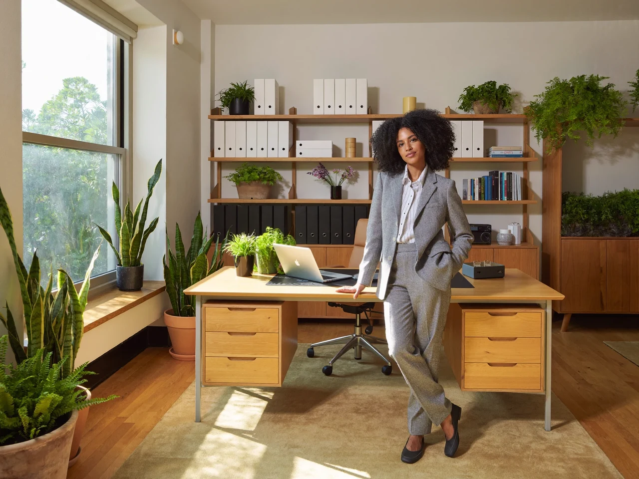 Helles Büro mit Holzschreibtisch, Pflanzen und Regalen voller Ordner